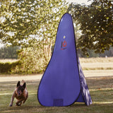 Dog running towards a large purple training blind in an outdoor setting with trees in the background.